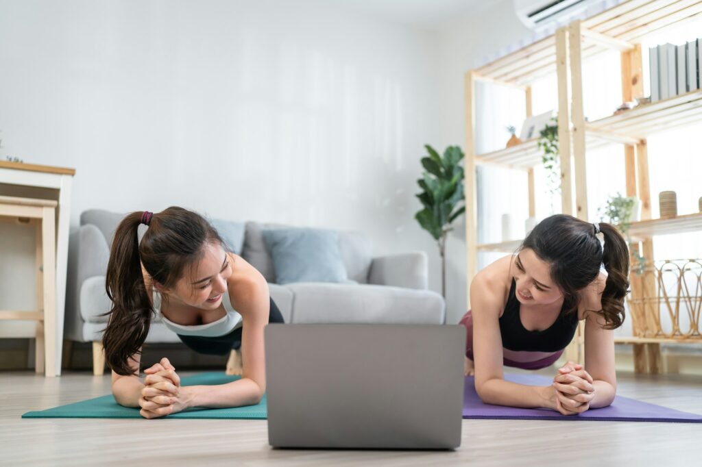 Asian active woman friend doing Yoga Pilates workout together at home.