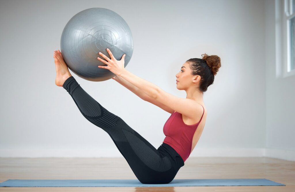 Pilates can be challenging. Shot of a young woman doing core exercises using a medicine ball.